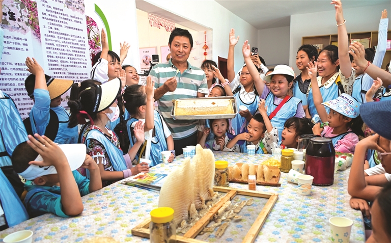 学生在呼图壁县五工台镇幸福村蜜蜂王国体验馆了解蜜蜂采蜜和蜂蜜制作过程